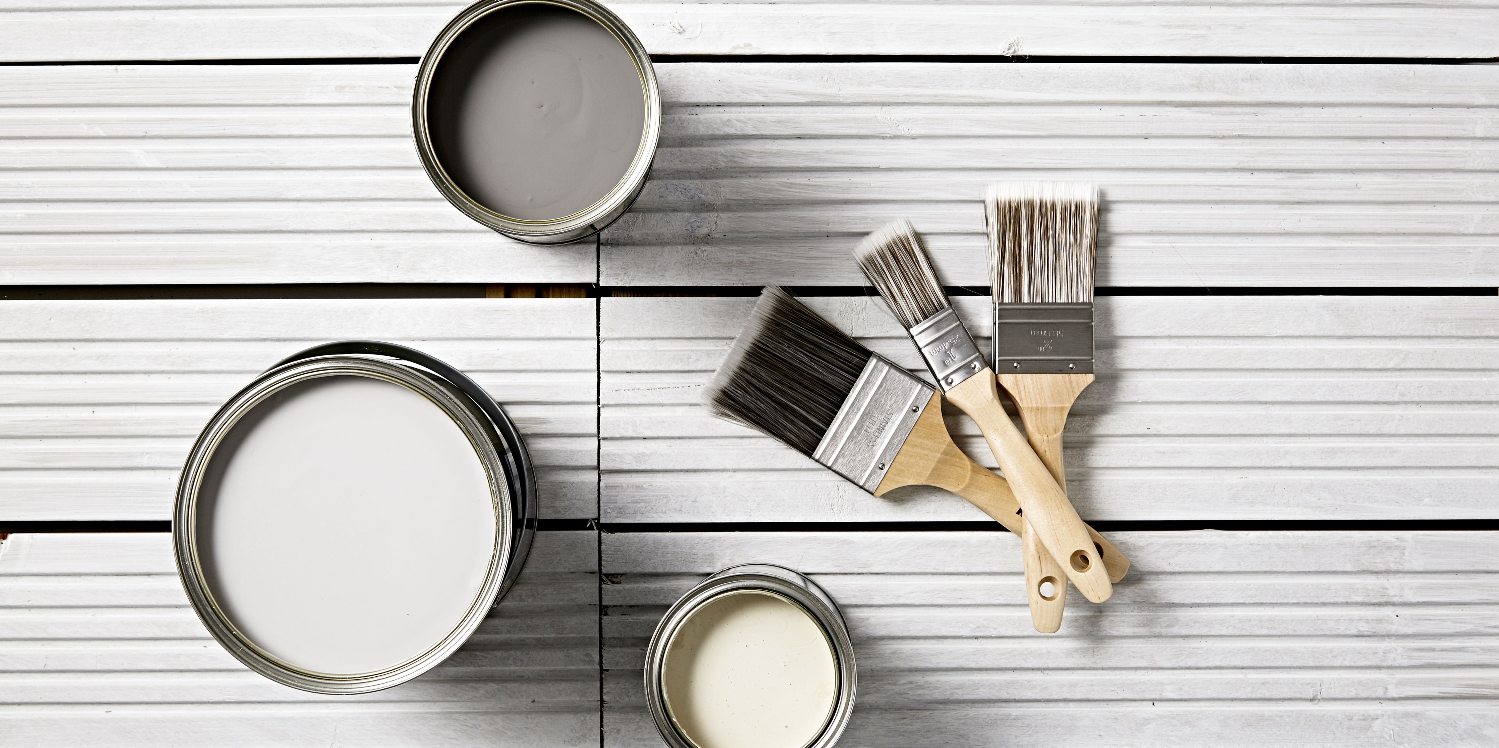 “A selection of grey paint in tins and some paint brushes”