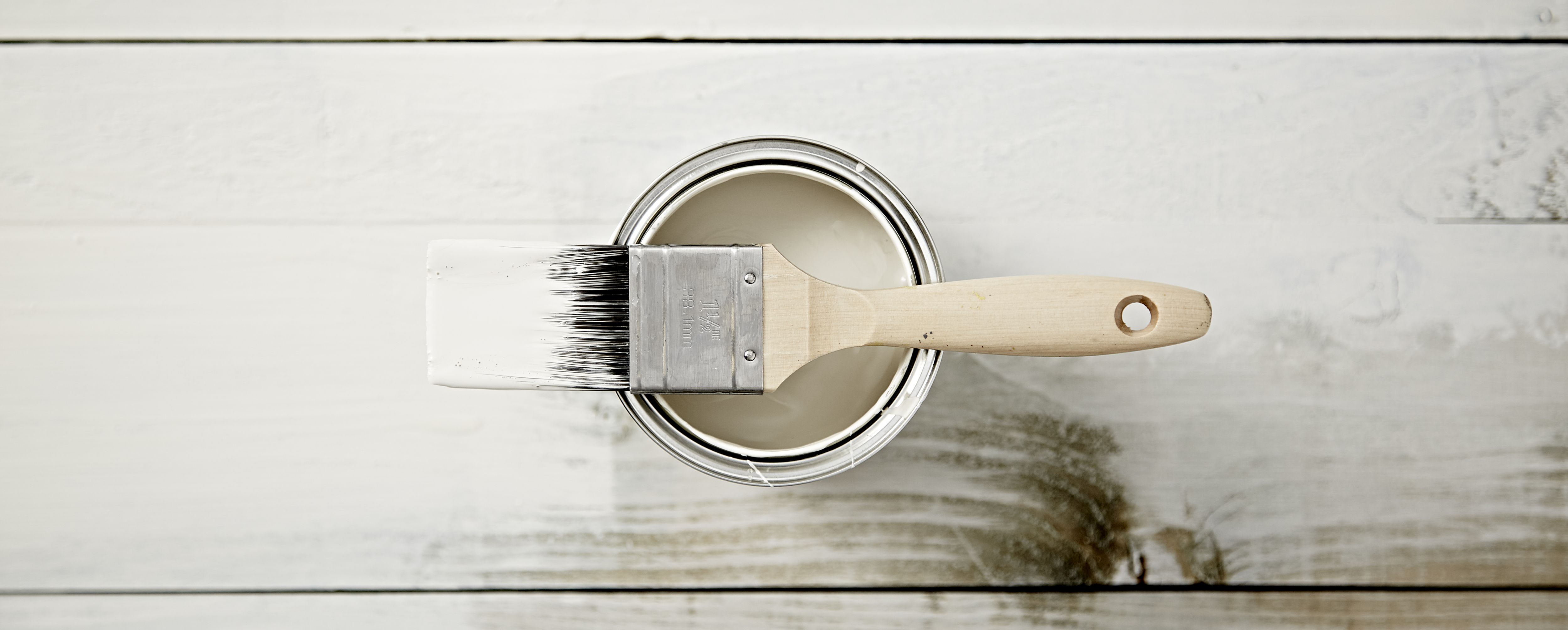 “A selection of grey paint in tins and some paint brushes”